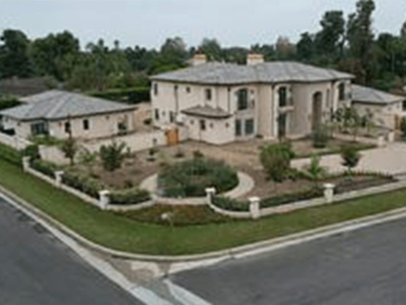 Luxurious two-story house with a landscaped yard, surrounded by a low stone wall