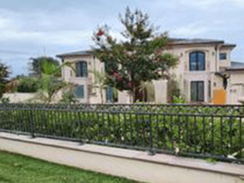 Elegant residential building with lush landscaping and a decorative fence.