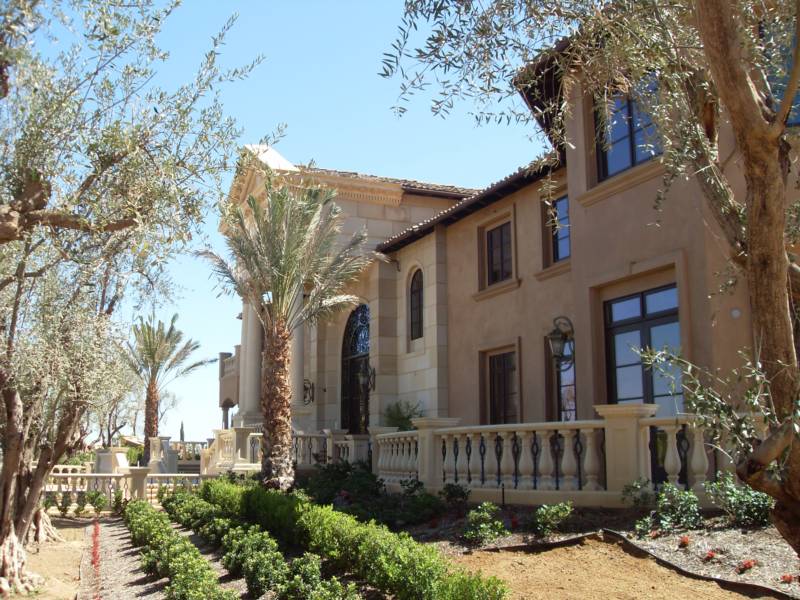 Elegant mansion surrounded by palm and olive trees